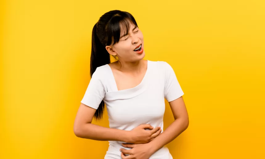 Woman experiencing stomach pain, set against a yellow background, symbolizing the impact of Congenital Diaphragmatic Hernia Repair.