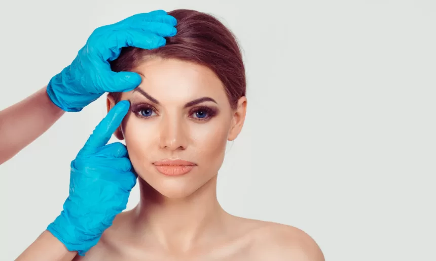 A woman receiving eyebrow shaping in a beauty salon, highlighting the art of eyelid surgery and brow enhancement.