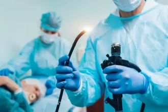 Two doctors in blue scrubs hold a torch, symbolizing guidance in Functional Endoscopic Sinus Surgery (FESS).