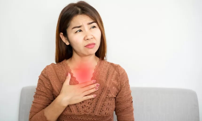 Woman experiencing chest pain, holding her heart, symbolizing the impact of GERD surgery on her health.
