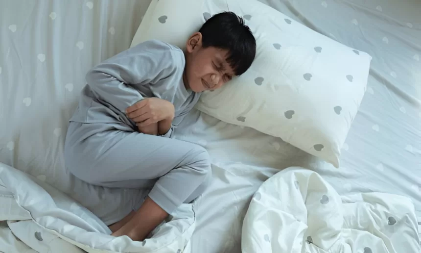 A young boy resting on a bed surrounded by pillows, recovering after Hirschsprung Disease surgery.