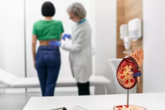 A woman stands beside a detailed model of a human kidney, illustrating the effects of hydronephrosis.
