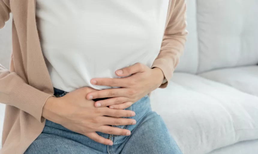 A woman gently resting her hands on her stomach, reflecting on her recent hysterectomy experience.