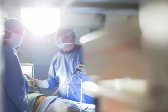 Two surgeons perform laparoscopic nephrectomy in a hospital room, focused on the surgical procedure.