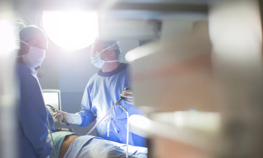 Two surgeons perform laparoscopic nephrectomy in a hospital room, focused on the surgical procedure.
