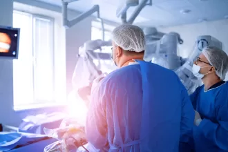 Two surgeons perform microsurgery on a patient in an operating room, focusing on nerve repair techniques.