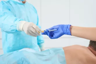 A patient in a blue gown receives an injection as part of Minimally Invasive Spine Surgery (MISS) treatment.
