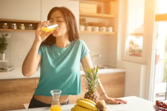 A woman enjoying a refreshing glass of orange juice, symbolizing a healthy morning routine.