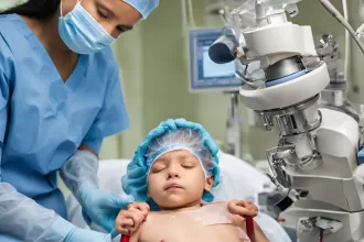 A woman in scrubs gently holds a child, symbolizing care in neonatal surgery for congenital anomalies.