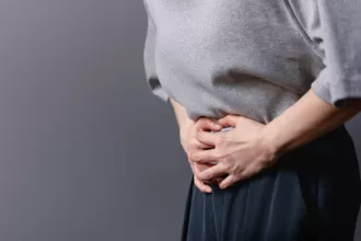 A woman gently rests her hands on her stomach, symbolizing strength and resilience during her ovarian cancer surgery journey.