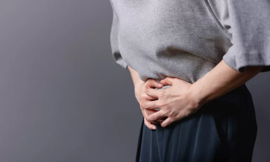 A woman gently rests her hands on her stomach, symbolizing strength and resilience during her ovarian cancer surgery journey.