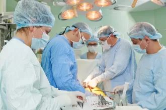 A team of medical professionals in surgical attire performing pediatric cardiac surgery on a patient.
