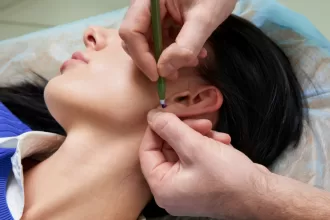A person receiving an ear piercing, showcasing the procedure in a clinical setting with professional equipment.