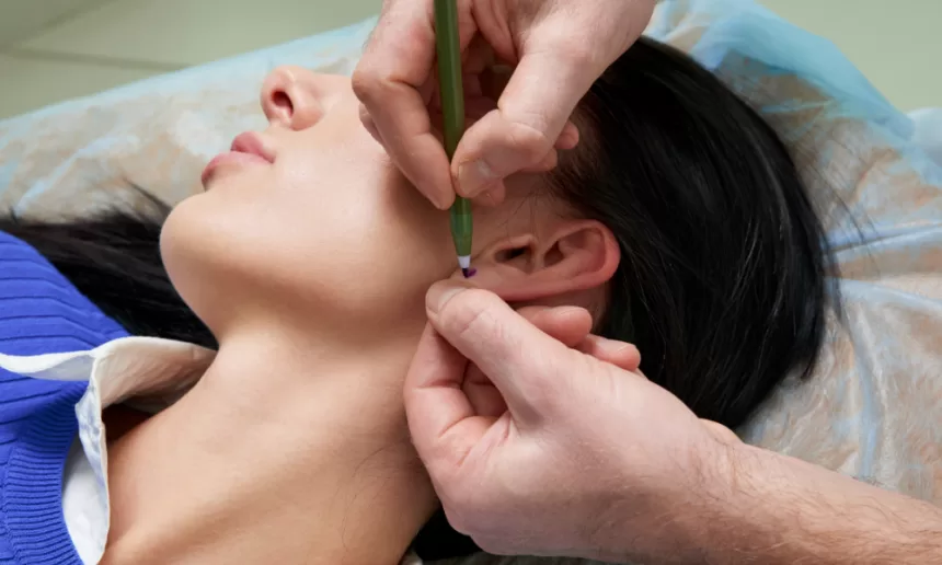 A person receiving an ear piercing, showcasing the procedure in a clinical setting with professional equipment.