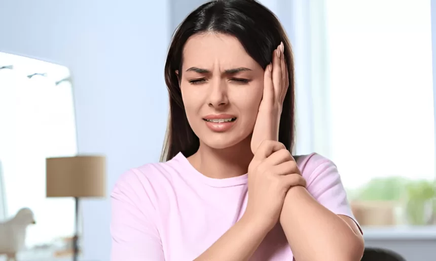 A woman holds her ear in discomfort, highlighting the impact of ear pain related to stapedectomy surgery.