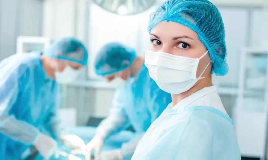 A woman in a surgical gown and mask prepares for thoracic surgery, focusing on lung resection and pleurectomy procedures.