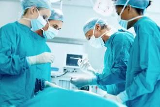Surgeons in blue scrubs perform pancreas surgery in a sterile operating room, focused on the intricate procedure.