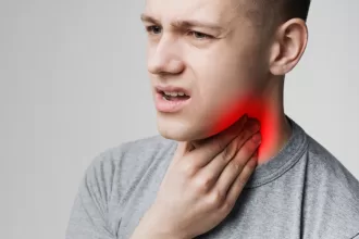 A man with a sore throat and a red spot on his neck, indicating possible tonsillectomy or adenoidectomy recovery.