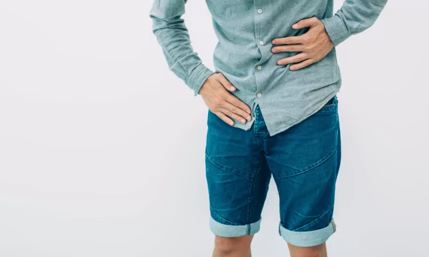 A man resting his hands on his stomach, reflecting on his recent ureteral reimplantation surgery.