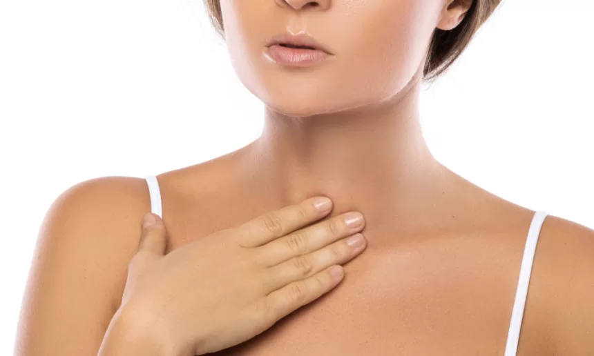 A woman gently holds her neck, reflecting on her recent vocal cord surgery for nodules and polyps.
