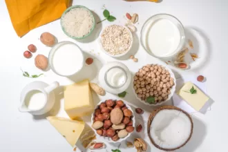 Various plant-based yogurt alternatives like almond, coconut, and soy yogurt in glass bowls with fresh fruits on a wooden table.
