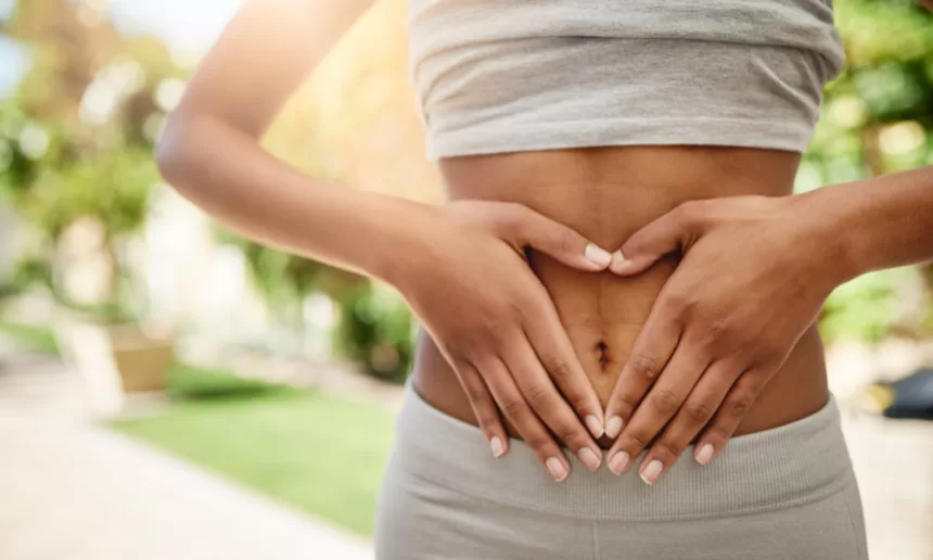 A woman gently rests her hands on her stomach, symbolizing recovery after an abdominoplasty procedure.