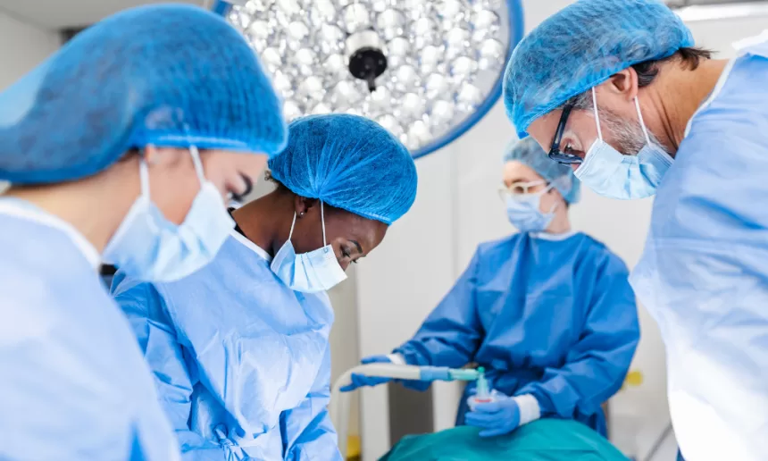A surgeon performing minimally invasive cardiac surgery with advanced robotic tools in a sterile operating room.
